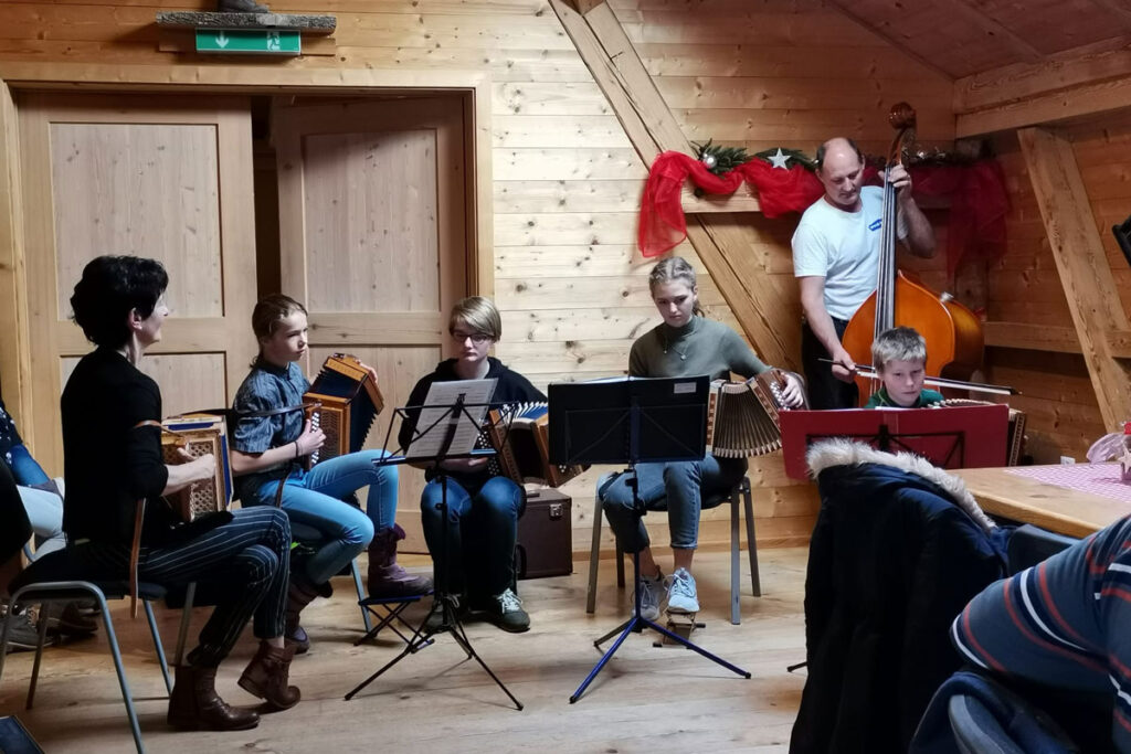 Drei Musikschüler spielen mit der Musiklehrerin und einem Bassisten